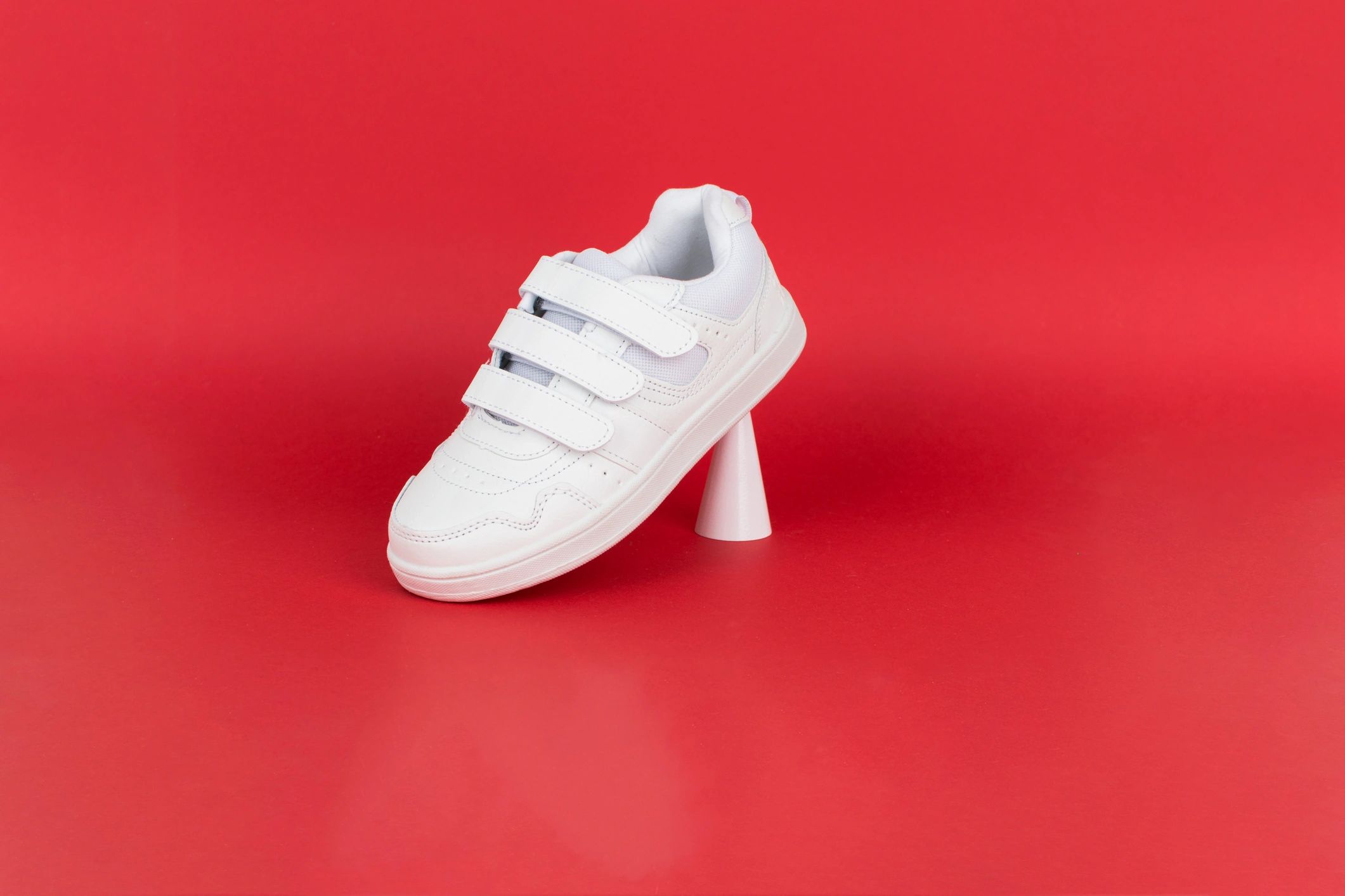 White sneakers on a red background representing sports gear deals